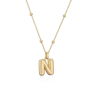 Vue macro du pendentif lettre N dorée style ballon avec chaîne à billes délicate et brossée