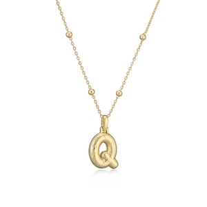 Détail macro du collier avec pendentif lettre Q dorée et finition en métal brossé