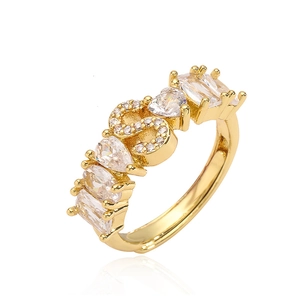 Dettaglio di un anello dorato con zirconi a forma di cuore e lettera S in micro pavé