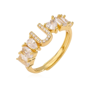 Dettaglio anello dorato con lettera U e pietre di zircone in varie forme brillanti