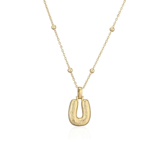 Détail d'un pendentif en métal martelé en forme de U doré sur une chaîne à billes