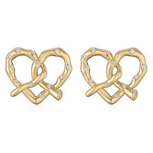 Detailed macro view of gold heart knot stud earrings with shimmering zircon pavé stones