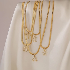 Detail van gouden slangenkettingen met met kristallen bezette dierenriem-hangers