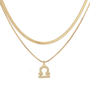 Detailed macro of golden Libra constellation pendant on layered herringbone snake chain