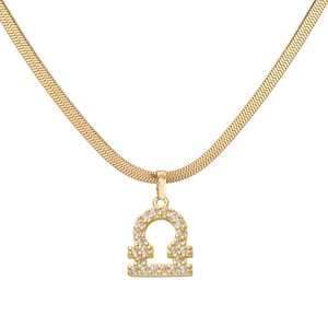 Macro-opname van de gouden Weegschaal hanger met kristallen op platte slangenketting
