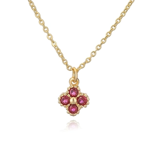 Macro shot of gold clover pendant with four red gemstones on a polished O-link chain