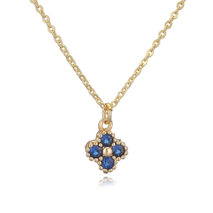 Close-up of gold clover necklace with deep blue gemstones and intricate flower pendant