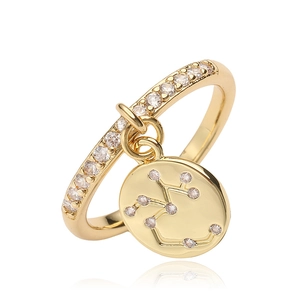 Detail of gold constellation ring with pavé cubic zirconia and hanging zodiac charm