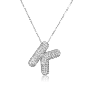 Macro del ciondolo a lettera K in argento con zirconi scintillanti su una sottile catena a O