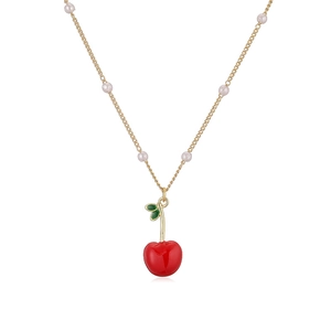 Close-up of cherry pendant necklace with gold chain and small white pearls detail