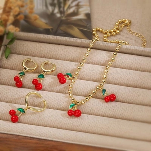 Vista dettagliata del set di gioielli ciliegia con collana dorata, anello ed orecchini