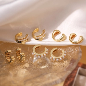 Detail of 18K gold plated C-shaped ear cuffs with pearls on elegant silk and glass
