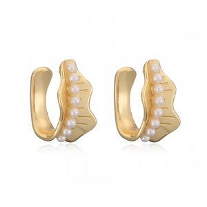 Close-up of gold-plated C-shaped ear cuffs with small white pearls and wavy texture