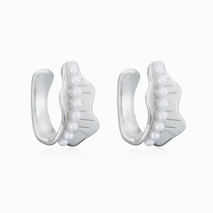 Detailed view of wave-shaped 18K gold plated copper ear cuffs with white inlaid pearls