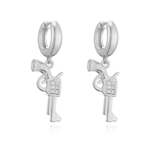 Detail view of silver metal pistol charm earrings with cubic zirconia on white background