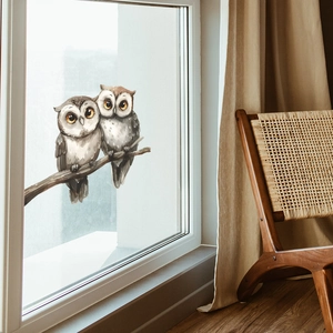 Close-up of watercolor owl window stickers on glass with a cozy home background