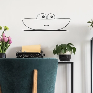 Minimalist peeking facial expression wall sticker above a retro typewriter and green velvet chair