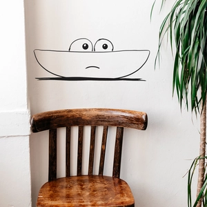 Minimalist cartoon wall decal with cute line art above a vintage wooden chair decor
