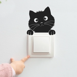 Detail showing a cute black cat cartoon wall sticker placed above a white light switch
