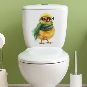 Détail d'un autocollant poussin 3D avec lunettes sur un couvercle de toilette blanc