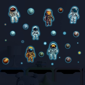 Luminous astronaut and planet wall stickers glowing blue in a dark boys bedroom