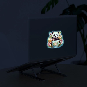 Luminous cartoon panda in tea cup sticker applied on a black laptop cover