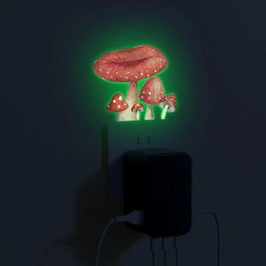 Luminous red mushroom night light glowing green on a wall socket for kids room decor
