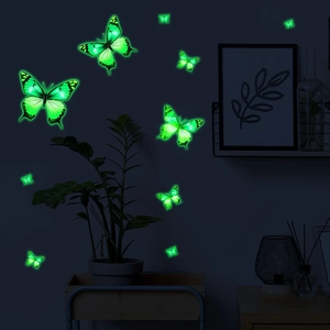 Detailed view of glowing green butterfly wall stickers on a dark bedroom wall