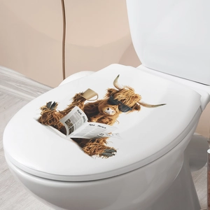 Close-up of highland cow reading newspaper sticker applied on a white toilet lid