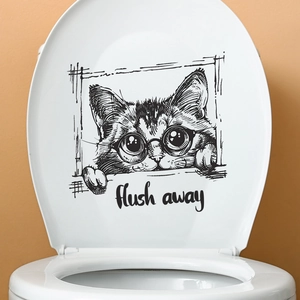 Close-up of cute cat decal with glasses and flush away text on white toilet lid