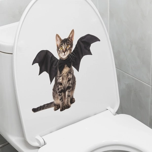 Detailed view of a 3D tabby cat sticker with bat wings on a white bathroom toilet lid
