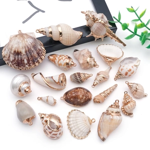 Dettaglio di pendenti in conchiglia naturale con bordi dorati e anelli metallici