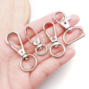 Silver metal lobster clasps and swivel hooks in four sizes shown for scale on a hand
