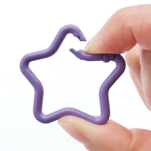 Star shaped purple alloy snap hook keychain connector shown being held by hand on white background