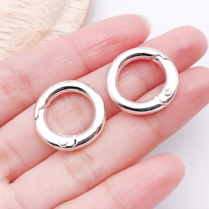 Detailed view of two polished silver alloy spring rings held in hand for bag strap repair