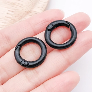 Detail view of two matte black spring gate rings held in hand to show size and texture
