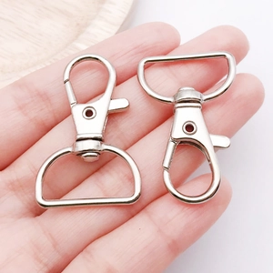 Close-up of polished silver alloy lobster clasps with D-ring connectors held by hand