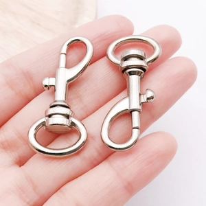 Close-up of polished silver metal swivel lobster clasps held in hand for size reference