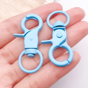Hand met lichtblauwe matte metalen karabijnsluitingen voor DIY-sieraden en sleutelhangers
