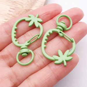 Dettaglio di moschettoni in metallo a forma di fragola verde chiaro con foglie