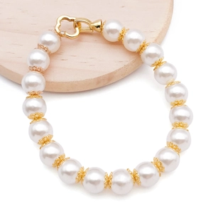 Elegant pearl bracelet with golden flower spacers and a heart-shaped clasp on a wood tray