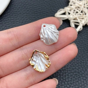 Macro detail of pearlescent shell charms for DIY jewelry with gold edges and holes