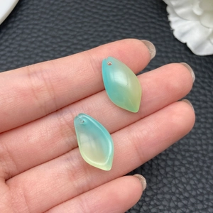 Detail of blue-green gradient lotus leaf pendants in hand showing size and texture