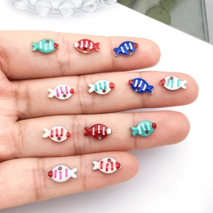 Kleurrijke emaille vis bedeltjes voor DIY sieraden maken getoond op een hand