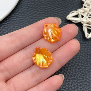 Macro detail of orange shell-shaped acrylic pendants with iridescent pearl finish for DIY jewelry