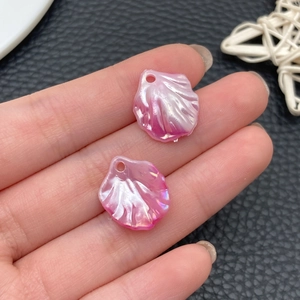 Detail view of two pink shell-shaped acrylic beads with iridescent finish for DIY jewelry