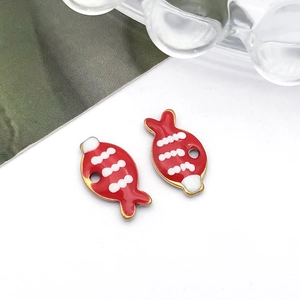 Detail van rode emaille visbedeltjes voor DIY-sieraden met vergulde randen en witte golven