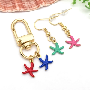 Détails de breloques étoiles de mer en émail coloré sur porte-clés et boucles d'oreilles dorés