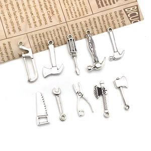 Vue macro de 10 breloques outils en alliage argenté comprenant marteaux et scies pour DIY