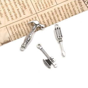 Vue rapprochée de pendentifs outils en alliage argenté vieilli avec détails de marteau